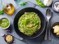 Pyszne spaghetti z pesto, idealne co na obiad zamiast mięsa. Podane z parmezanem, orzeszkami pinii i świeżą bazylią.