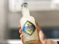 Ręka trzyma butelkę Seth & Riley's GARAGE Hard Lemon, orzeźwiający drink z piwem.