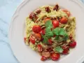 Pyszne dietetyczne spaghetti z cukinii z pomidorkami koktajlowymi i suszonymi pomidorami, udekorowane świeżą kolendrą.