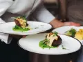 Elegancko podany obiad: soczysty kawałek mięsa na zielonym purée, polany sosem. Idealny przykład, jak podać obiad w wykwintny sposób.