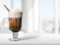 Pyszny irish coffee drink z bitą śmietaną i laską cynamonu, idealny na chłodny wieczór.
