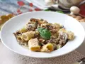 Pyszne spaghetti z grzybami w kremowym sosie, udekorowane listkiem bazylii. Idealne na jesienny obiad.