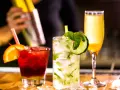 Mojito na białym rumie kontra Mojito na ciemnym. Trzy drinki: czerwony z pomarańczą, zielony z ogórkiem i żółty.