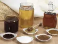 Domowy syrop cukrowy i kupny syrop barmański obok miodu i cukru.