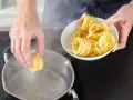 Ręka wkłada tagliatelle do wrzącej wody. Kluczowe jest, na jakim ogniu gotować makaron, by był al dente.