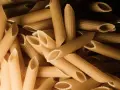 Stos makaronu penne, czy to orkiszowy czy żytni, czeka na gotowanie.