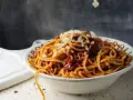 Gorące spaghetti z sosem bolońskim i parmezanem, parujące w misce. Czy to bucatini czy spaghetti, smakuje wyśmienicie!