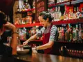 Uśmiechnięta barmanka przygotowuje drinki za ladą pełną alkoholi. Ciekawe, ile zarabia barman w Turcji?