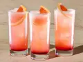 Trzy orzeźwiające drinki: Tequila Sunrise i Paloma, z plasterkami grejpfruta i lodem.