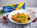 Pyszny talerz makaronu spaghetti bezglutenowego z pesto, pomidorkami i migdałami. Obok pudełko makaronu.