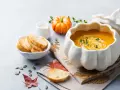 Zupa krem z dyni w naczyniu w kształcie dyni, podana z grzankami i śmietanką. Idealna na jesienne dni.