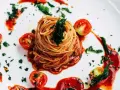 Eleganckie spaghetti bez mięsa, podane z sosem pomidorowym, świeżymi pomidorkami koktajlowymi i posypane ziołami.