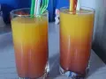 Dwa orzeźwiające drinki z sokiem malinowym, tworzące piękny gradient od czerwieni do żółci, gotowe do degustacji.