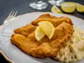 Złocisty sznycel cielęcy i kotlet schabowy, podane z cytryną i sałatką jarzynową. Pyszny obiad!