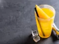 Orzeźwiający drink z wódką i sokiem pomarańczowym, ozdobiony plasterkiem pomarańczy, z kostkami lodu i miarką barmańską obok.