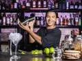 Uśmiechnięty barman miesza drinka. Chcesz wiedzieć, jak zostać barmanem kobietą? Zacznij od nauki sztuki miksowania!