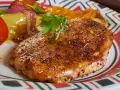 Apetyczny kotlet schabowy lub z piersi kurczaka, podany z pieczonymi warzywami i pomidorem.