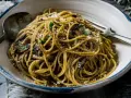 Makaron spaghetti z grzybami i parmezanem, posypany natką pietruszki. Pyszne danie gotowe do spożycia.