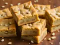 Słodkie brownie i blondie z orzechami makadamia, ułożone na drewnianej desce.