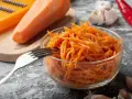 Pyszna surówka z marchewki jak z restauracji, gotowa do podania. Obok marchewka, tarka, czosnek i papryczka chili.