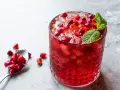 Orzeźwiający drink z grenadyną i rumem, ozdobiony świeżymi pestkami granatu i miętą. Idealny na letnie wieczory.