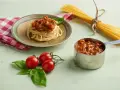 Pyszne spaghetti z sosem bolońskim, przygotowane z pomocą przyprawy do spaghetti Knorr. Obok świeże pomidory i bazylia.