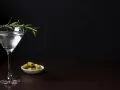Elegancki kieliszek z drinkiem, gałązka rozmarynu i oliwki. Czy to Dirty Martini, czy klasyczne Dry Martini?