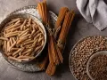 Jasny makaron penne w misce i ciemny makaron spaghetti na talerzu, obok ciecierzycy.