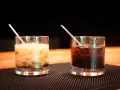 Dwa drinki z likierem kawowym na barze. Jeden kremowy, drugi ciemny, oba z lodem i słomką.