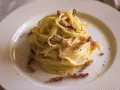 Pyszne spaghetti carbonara, idealne na prosty przepis. Kremowy sos, chrupiący boczek i czarny pieprz na talerzu.