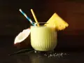 Orzeźwiający drink z mlekiem, kokosem i ananasem, ozdobiony plasterkiem owocu i kolorowymi słomkami. Idealny na tropikalne popołudnie.