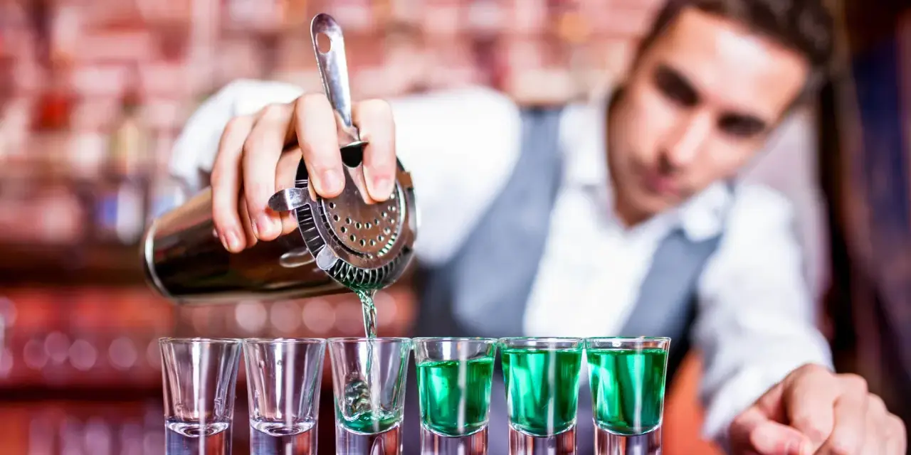 Barman nalewa zielony shot. Chcesz wiedzieć, jak zostać barmanem? To pierwszy krok do mistrzostwa!