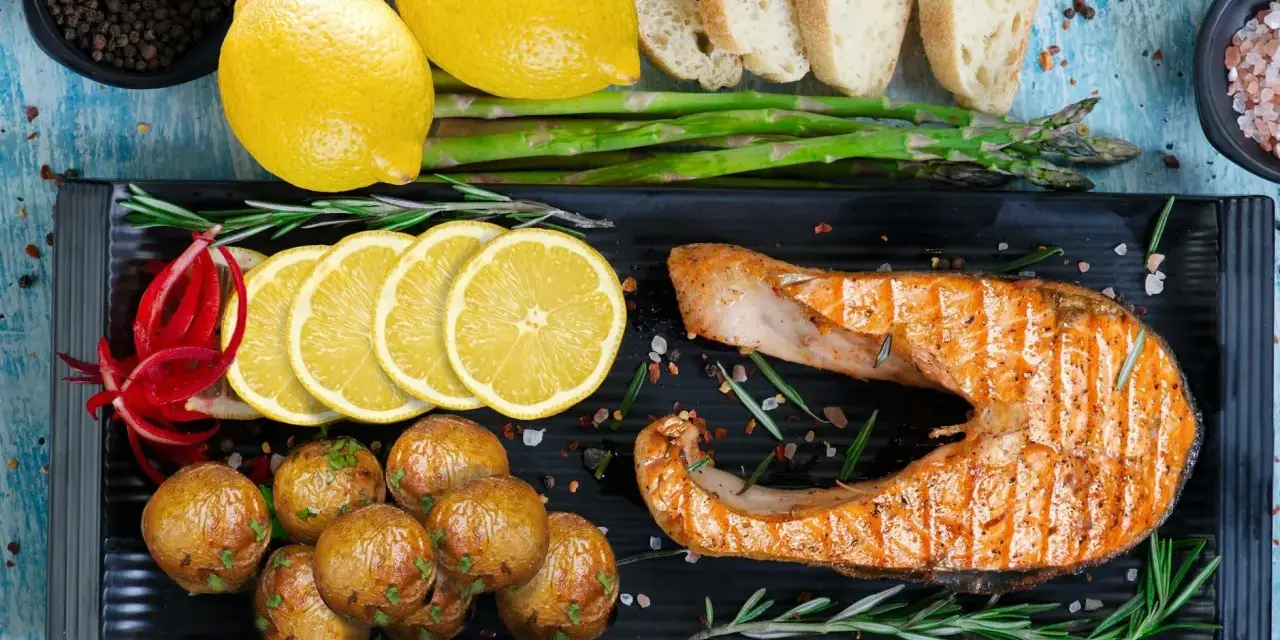 Grillowany łosoś z ziemniaczkami, cytryną i szparagami to idealny pomysł na obiad.