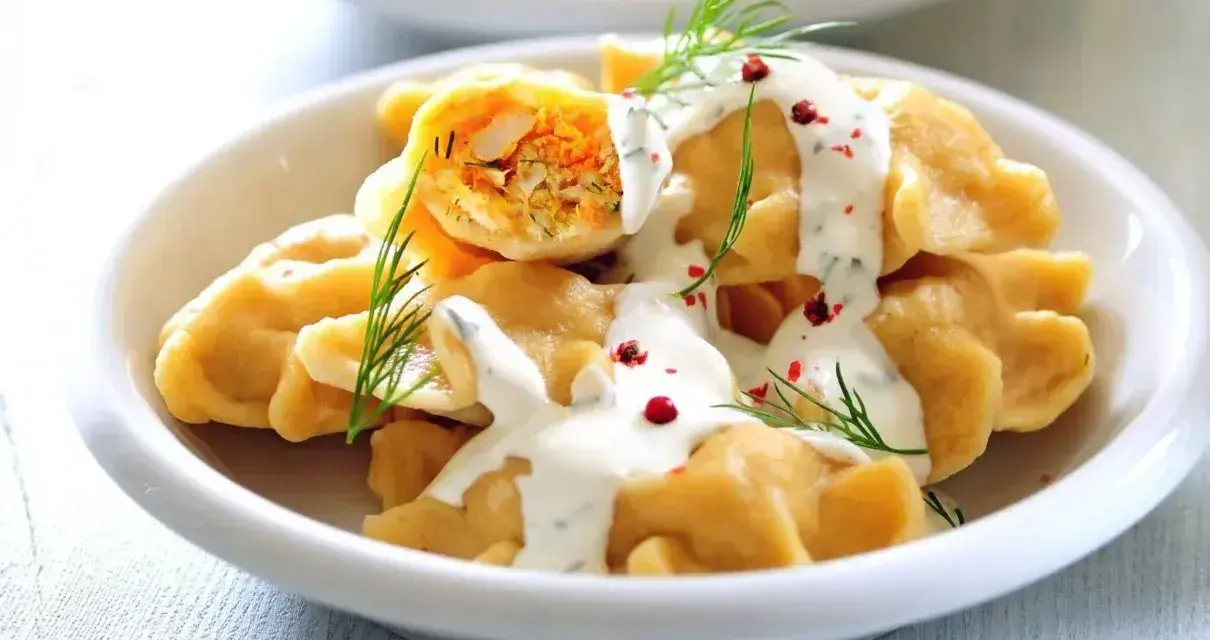 Pyszne pierogi z farszem, polane sosem i posypane koperkiem. Idealne co na obiad dla gości, by ich zachwycić.