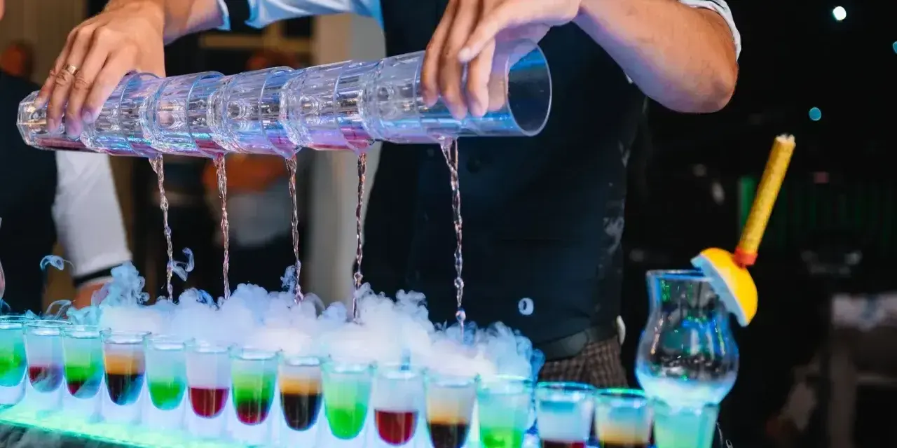 Barman nalewa kolorowe shoty na weselu. Zastanawiasz się, ile bierze barman na weselu za taką atrakcję?