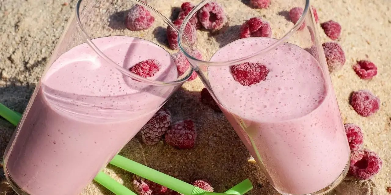 Dwa pyszne, różowe drinki z jajkiem i malinami na piasku. Idealne na letnie orzeźwienie.