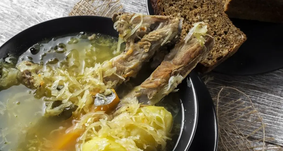 Kapuśniak ze świeżej kapusty czy kwaśnica? Aromatyczna zupa z żeberkami, ziemniakami i kiszoną kapustą, podana z ciemnym chlebem.