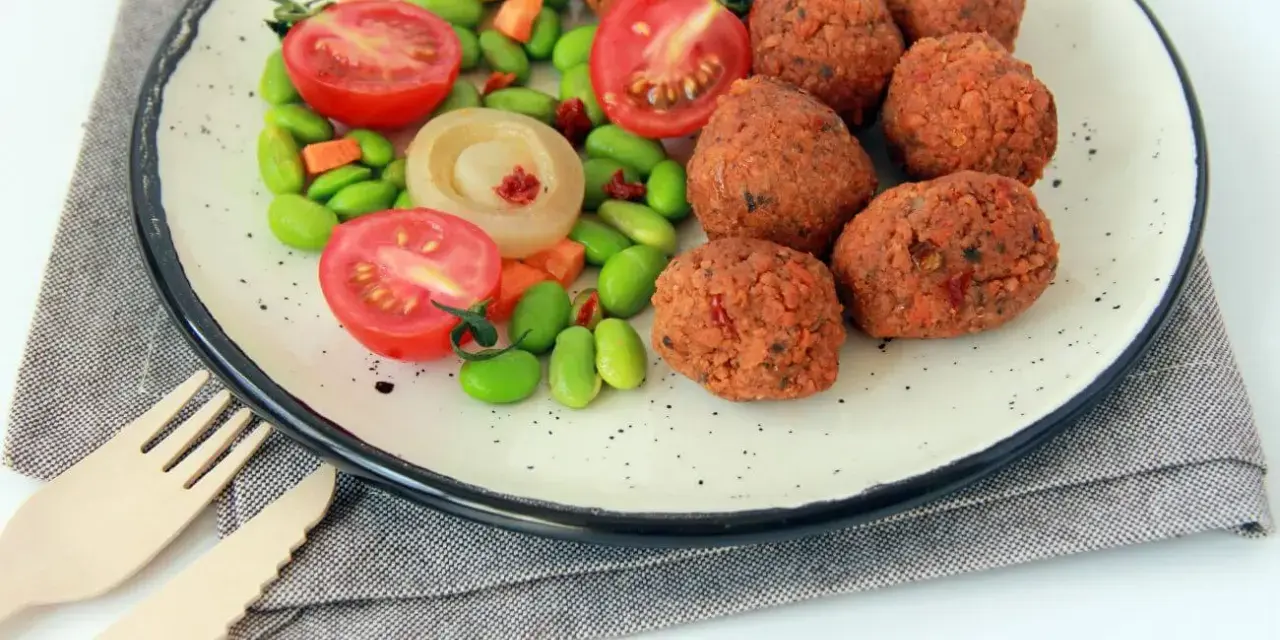 Falafel kontra kotlety sojowe: chrupiące kulki falafela i soczyste pomidorki z edamame na talerzu.