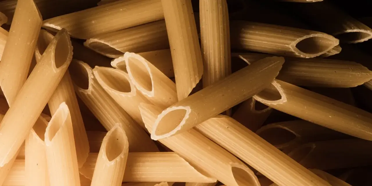 Stos makaronu penne, czy to orkiszowy czy żytni, czeka na gotowanie.