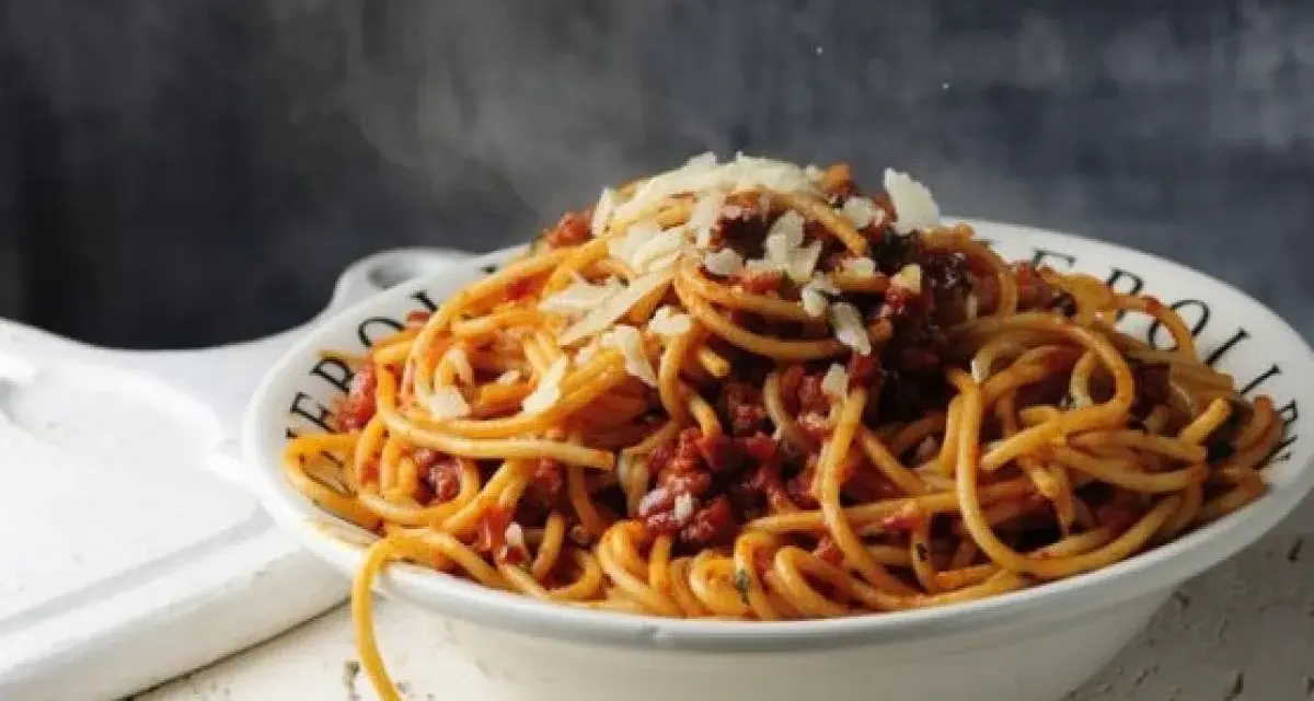 Gorące spaghetti z sosem bolońskim i parmezanem, parujące w misce. Czy to bucatini czy spaghetti, smakuje wyśmienicie!