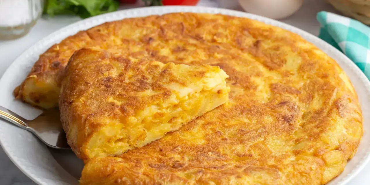 Złocista tortilla ziemniaczana, idealna na szybki obiad z niczego. Na talerzu, obok pomidorów i jajek.