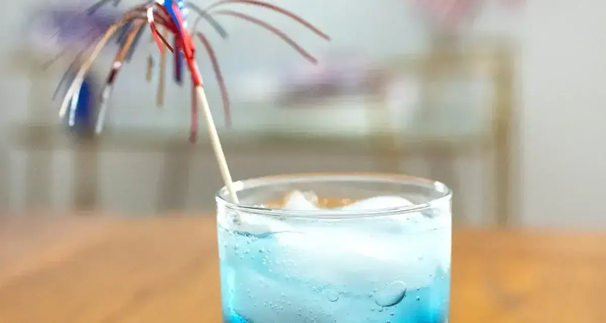 Niebieski drink z lodem i parasolką, przypominający letni koktajl z blue curacao.