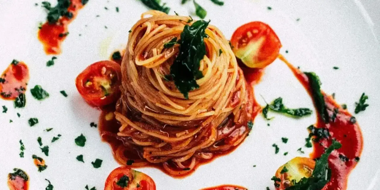 Eleganckie spaghetti bez mięsa, podane z sosem pomidorowym, świeżymi pomidorkami koktajlowymi i posypane ziołami.