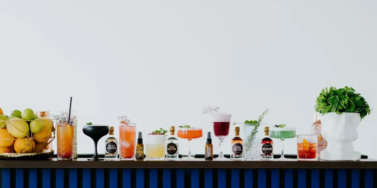 Kolorowe drinki z adwokatem i buteleczki z alkoholami na barze.
