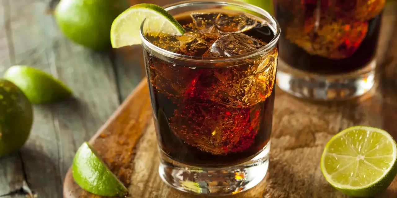 Orzeźwiający drink z rumem Bacardi, lodem i limonką na drewnianej desce.