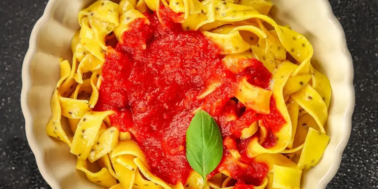 Pyszne linguine z sosem pomidorowym i listkiem bazylii. Makaron wygląda jak spaghetti, ale jest szerszy.