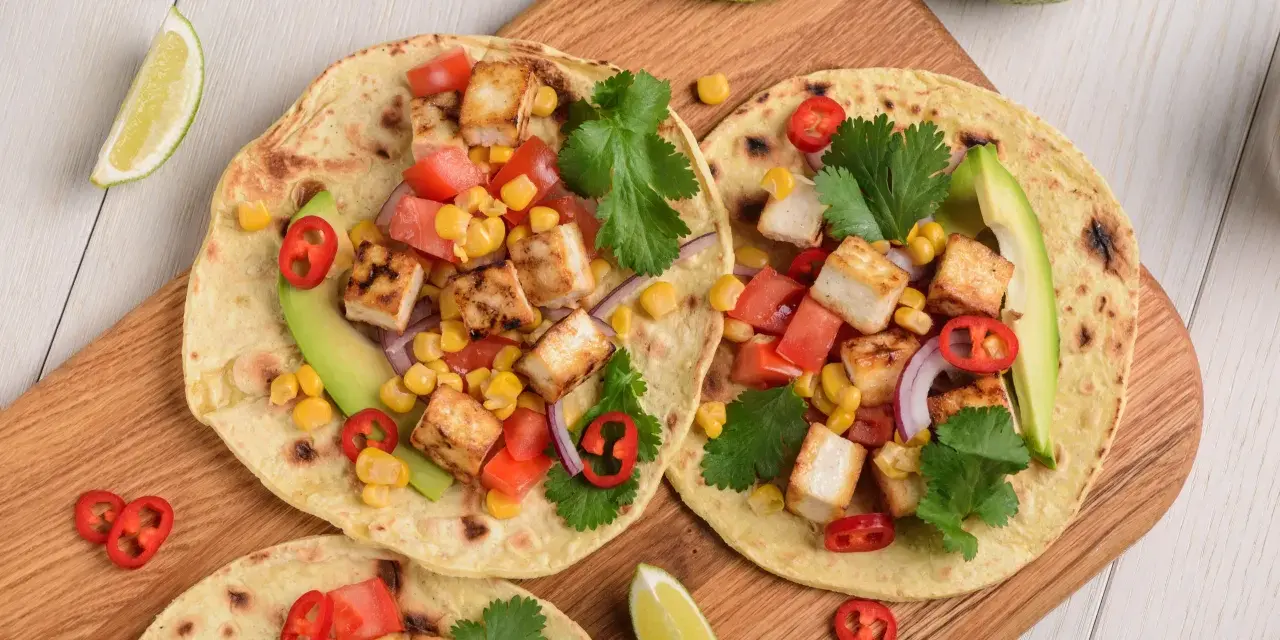 Zdrowy obiad dietetyczny: tortille z grillowanym tofu, kukurydzą, pomidorami, awokado i kolendrą.