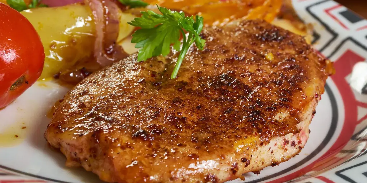 Apetyczny kotlet schabowy lub z piersi kurczaka, podany z pieczonymi warzywami i pomidorem.