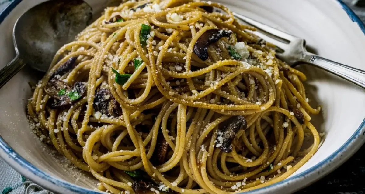 Makaron spaghetti z grzybami i parmezanem, posypany natką pietruszki. Pyszne danie gotowe do spożycia.