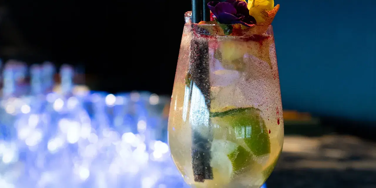 Orzeźwiający drink prosecco sprite z limonką i kwiatową dekoracją, idealny na letnie wieczory.